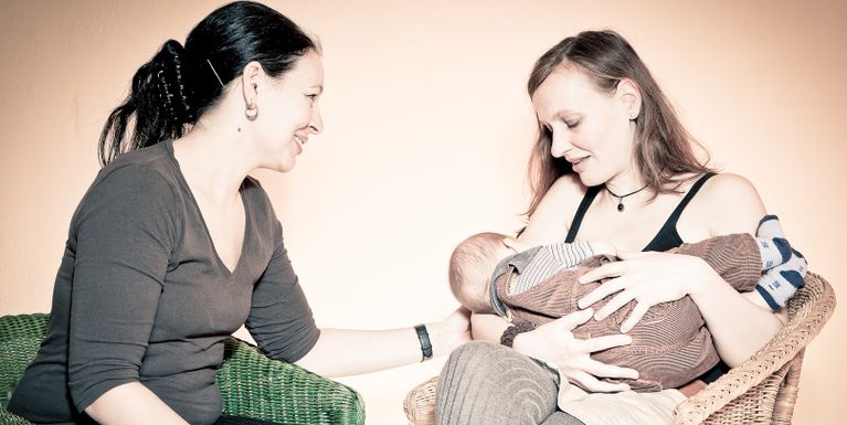 Therapeutin Dani Fraenkel mit einer Mutter als Klientin die ihr Baby stillt. Elterberatung zugewandt und liebevoll